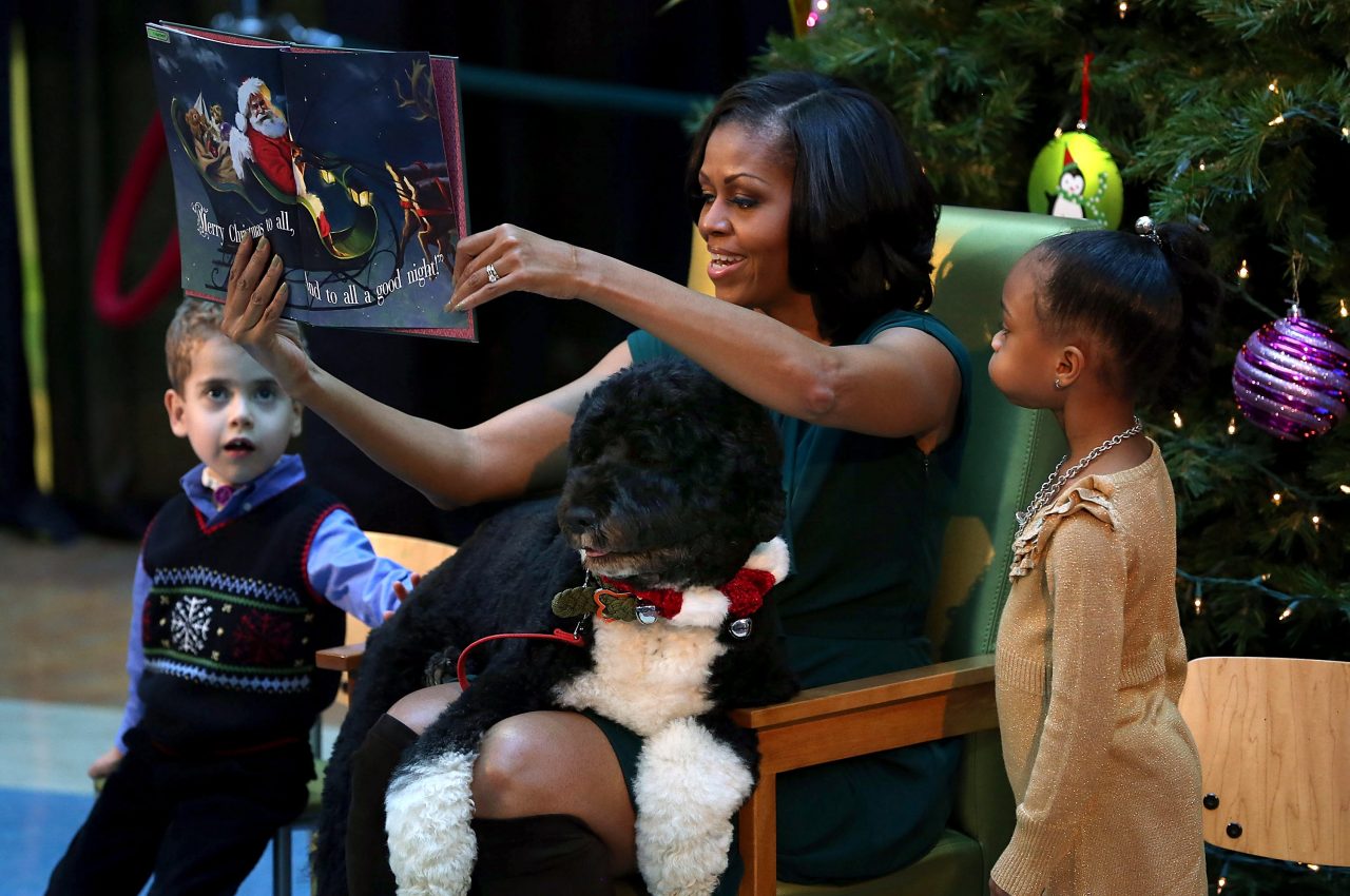 Becoming Michelle Obama-Dec 2012 Children's National Medical Center reading a Christmas book with dog Bo on her lap