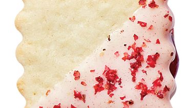 Raspberry sugar sandwich cookie dipped in white chocolate and covered in pink peppercorn