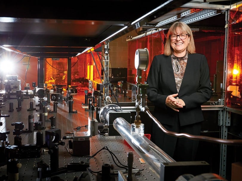 women of the year 2018: Donna Strickland poses for a portrait in front of her tech, wears glasses and black jacket