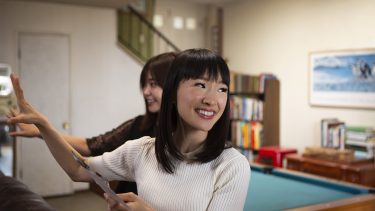 tidying up with marie kondo show: kondo gestures towards wall while smiling