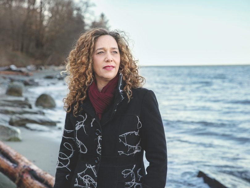 Tzeporah Berman Ms Chatelaine sits on a log by the ocean, looking out across the beach