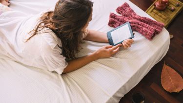 woman in bed reading kindle