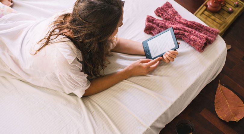 woman in bed reading kindle