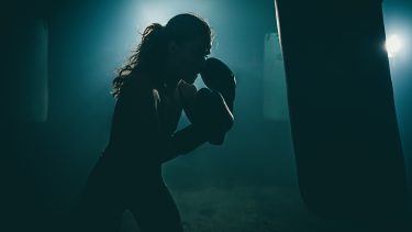 Woman boxes away her suppressed anger in moody lighting