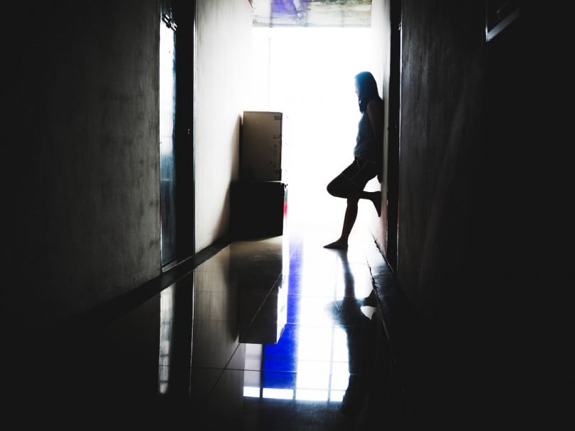 Out of the Shadows Timea Nagy book excerpt feature image shows a depress and hopeless woman standing the dark at corridor