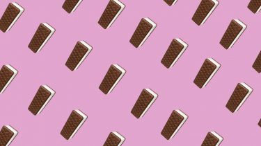 Ice cream sandwiches with chocolate cookies and vanilla ice cream against a pink background.