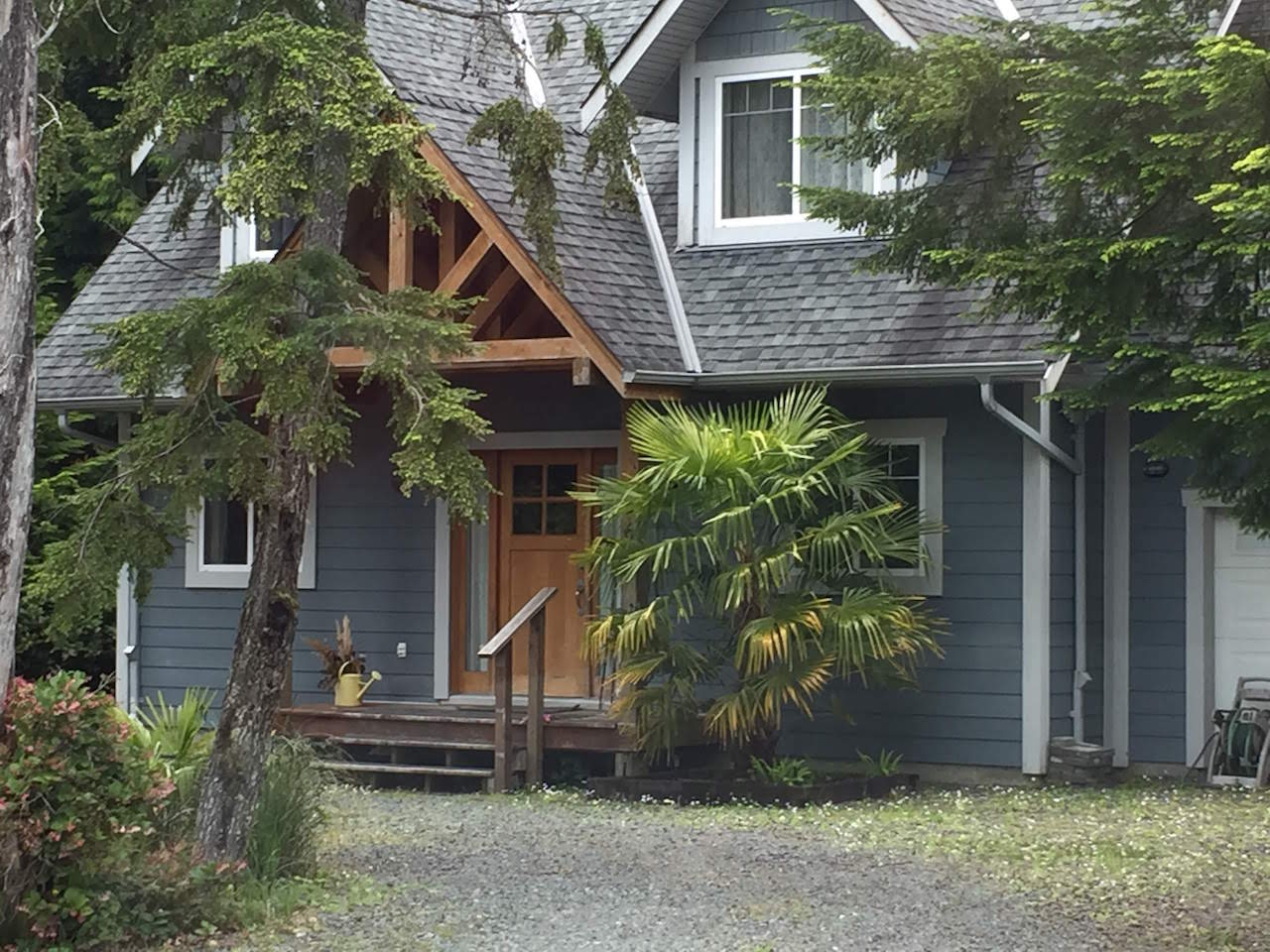 Outside shot of the front of a blue and grey home with pointed roof and wooden door