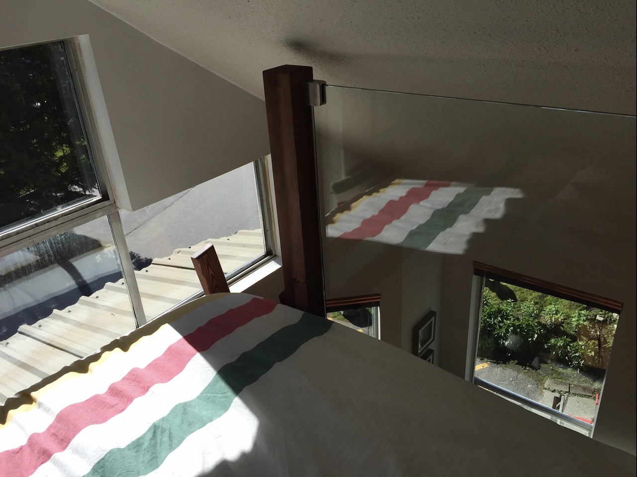 a photo of a tiny loft space with a queen mattress with a striped bed covering