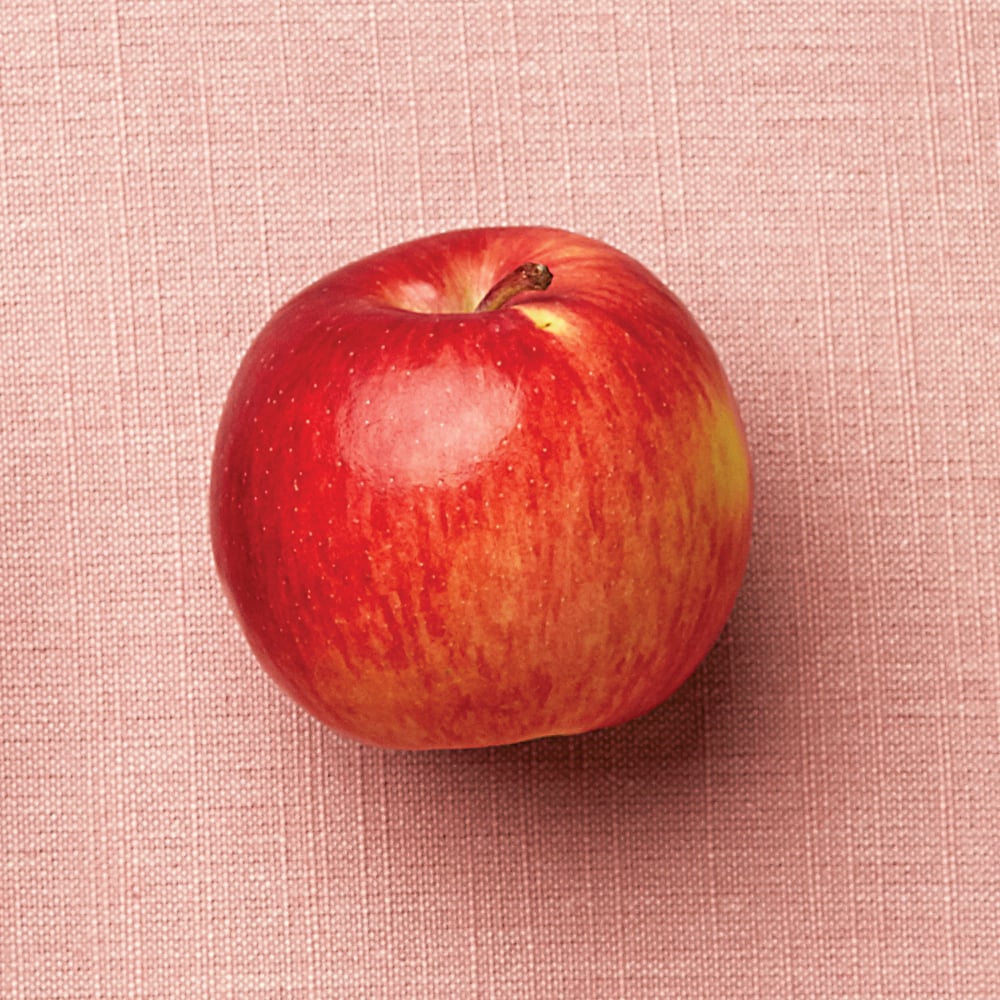 a red empire apple on a pink background