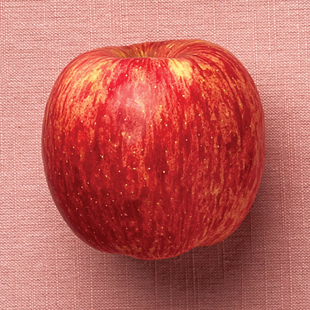 a Fuji apple on a pink background