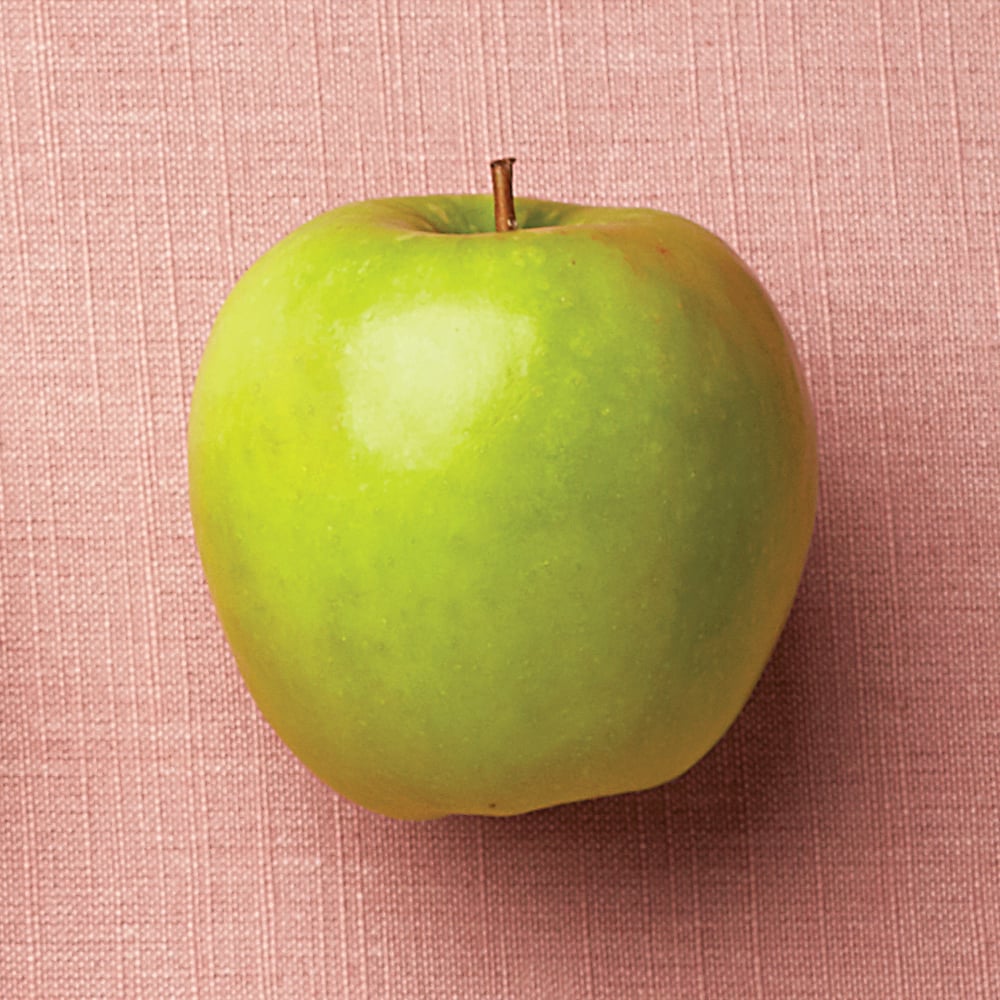 a green granny smith apple on a pink backdrop