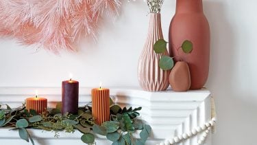 A white mantle decorated for the holidays with pink and terracotta accessories.