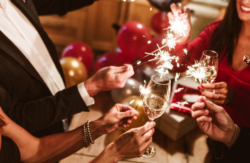 Friends holding sparklers toast with champagne to illustrate a piece on bargain sparkling wines