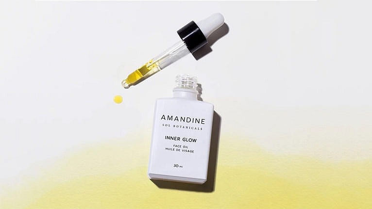 A bottle of Amandine Botanicals face oils, open on a grey and yellow background
