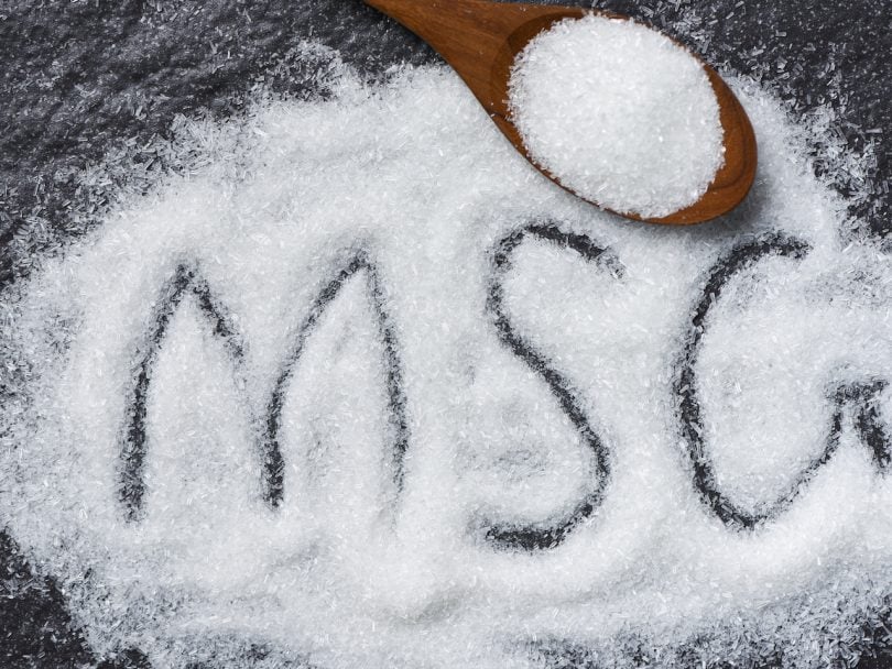 truth about MSG-Heap of monosodium glutamate on wooden spoon and dark background with text MSG