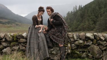 Outlander Reinvented My Sex Life-a man and a woman in 18th century Scotland sit on a stone wall close together