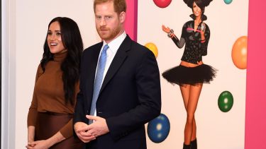 Prince Harry and Meghan Markle standing in front of art by Skawennati.