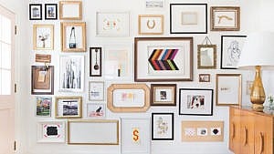 A photo of a gallery wall with mismatched frames on a white walll.