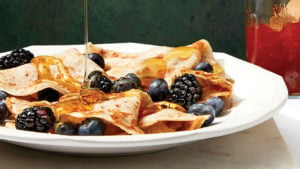 plate of oat milk vegan crepes with berries and syrup