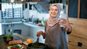 A Muslim woman video chats as she cooks