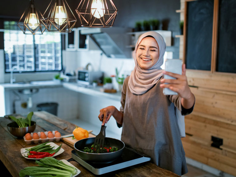A Muslim woman video chats as she cooks