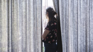 Woman looking outside the window during quarantine.