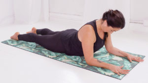 A woman demonstrating bedtime yoga to help you sleep on a floral yoga mat