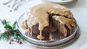 Curtis Stone's Sticky Toffee Pudding Cake on silver platter with toffee sauce drizzled overtop