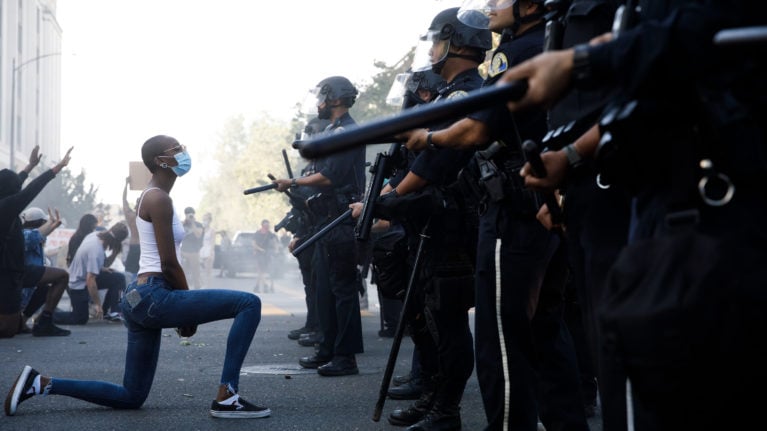 A protester takes a knee in front of San Jose Police officers during a protest on East Santa Clara Street in San Jose, Calif., on May 29, 2020, after the death of George Floyd in Minneapolis.