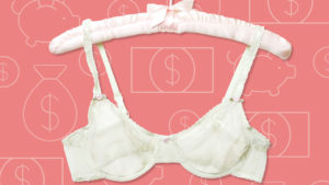White bra hanging on silk hanger on pink background.