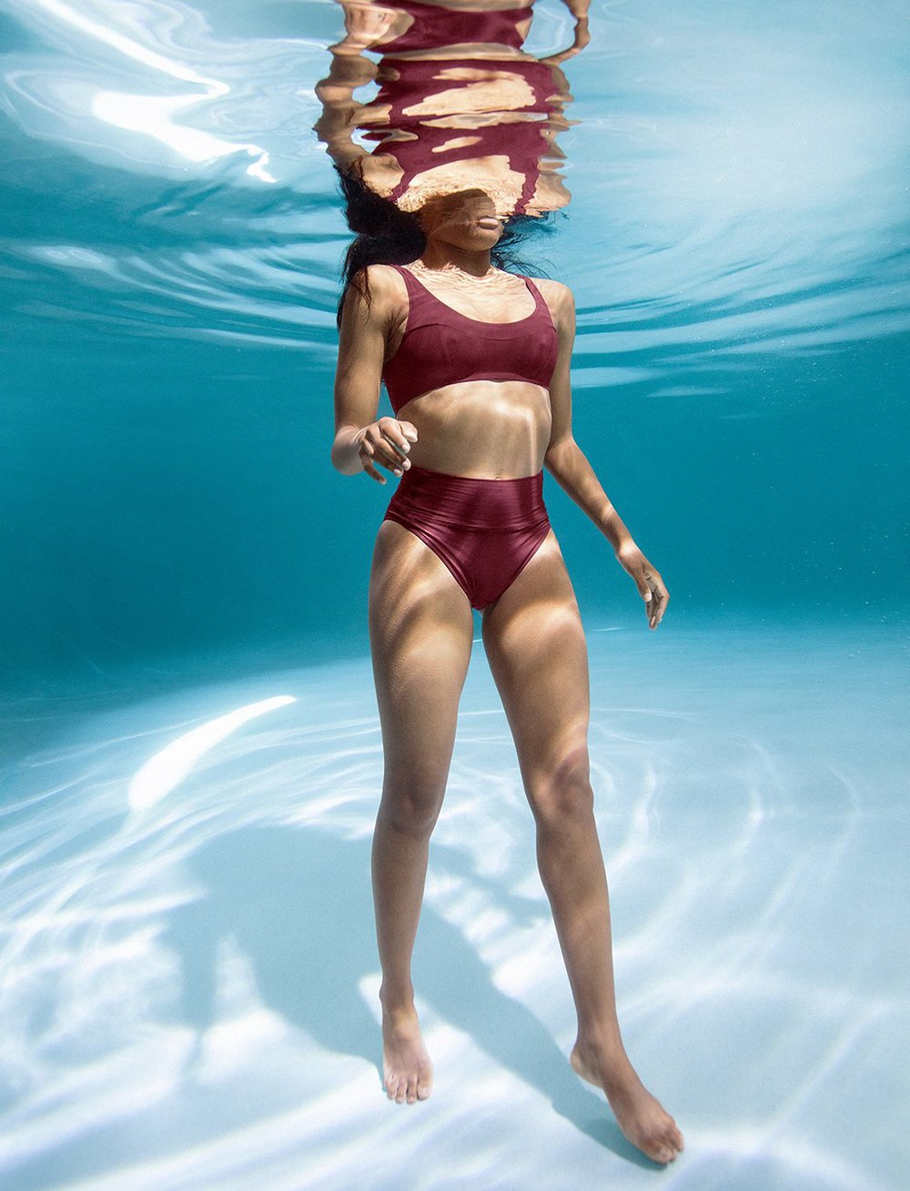 A model wearing a burgundy two-piece swimsuit from Fortnight under water.