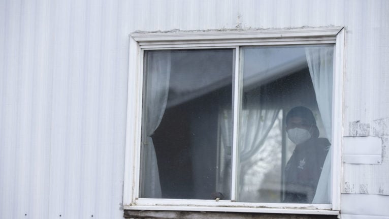 A migrant worker wearing a protective mask stands inside a trailer while starting a 14-day quarantine at a farm.