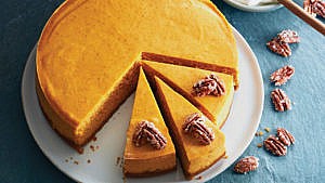 round pumpkin cheesecake with three slices cut and waiting to be served