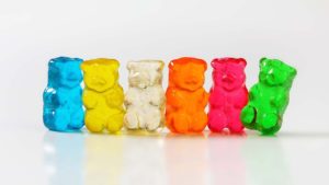 Gummy bears in assorted colours with the green gummy bear falling over