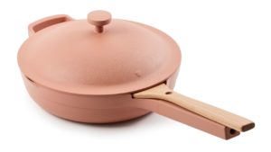 a pink pan with a wooden spatula on a white background