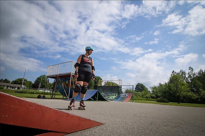 A woman in black shorts and a t shirt rollerskates at a skate park