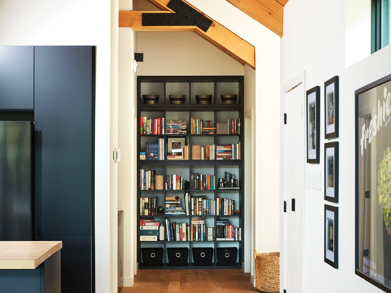 A black Ikea bookshelf tucked into the end of a hallway so that it looks custom-made for the nook.