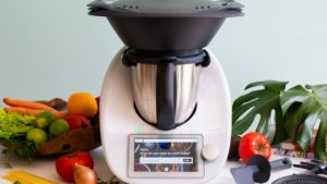 a thermomix machine on a kitchen counter with vegetables