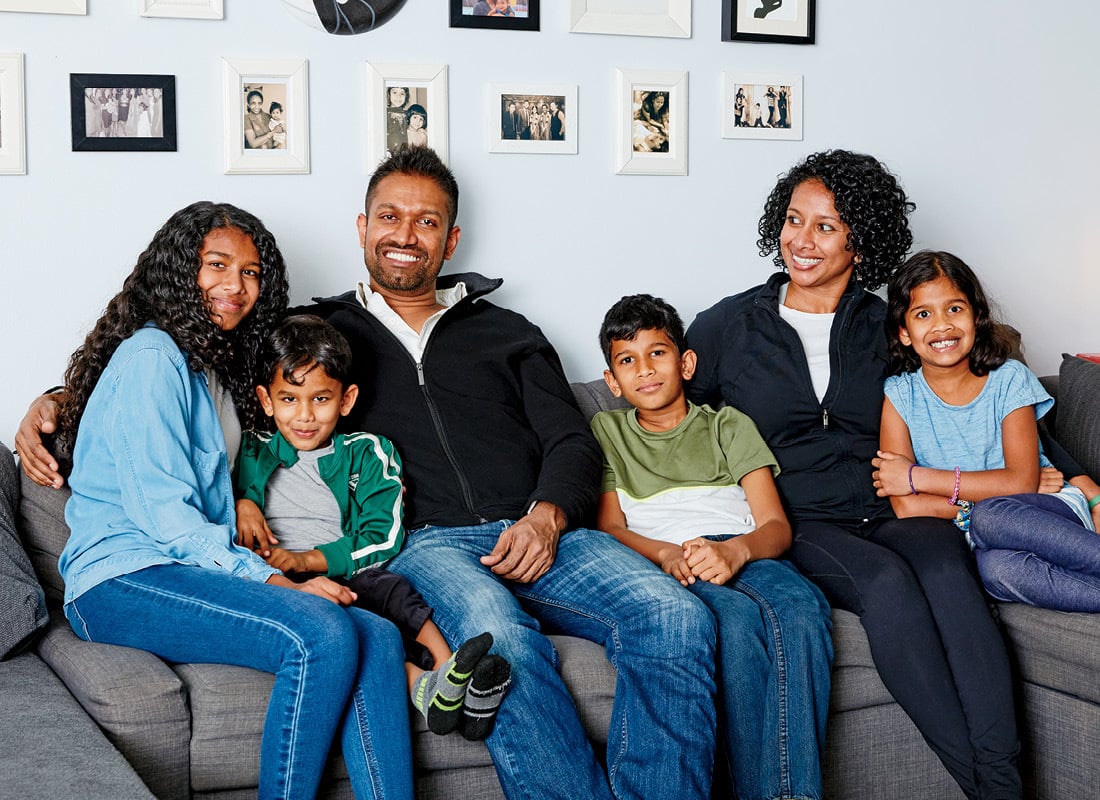 Family of six sits on a couch in their living room.