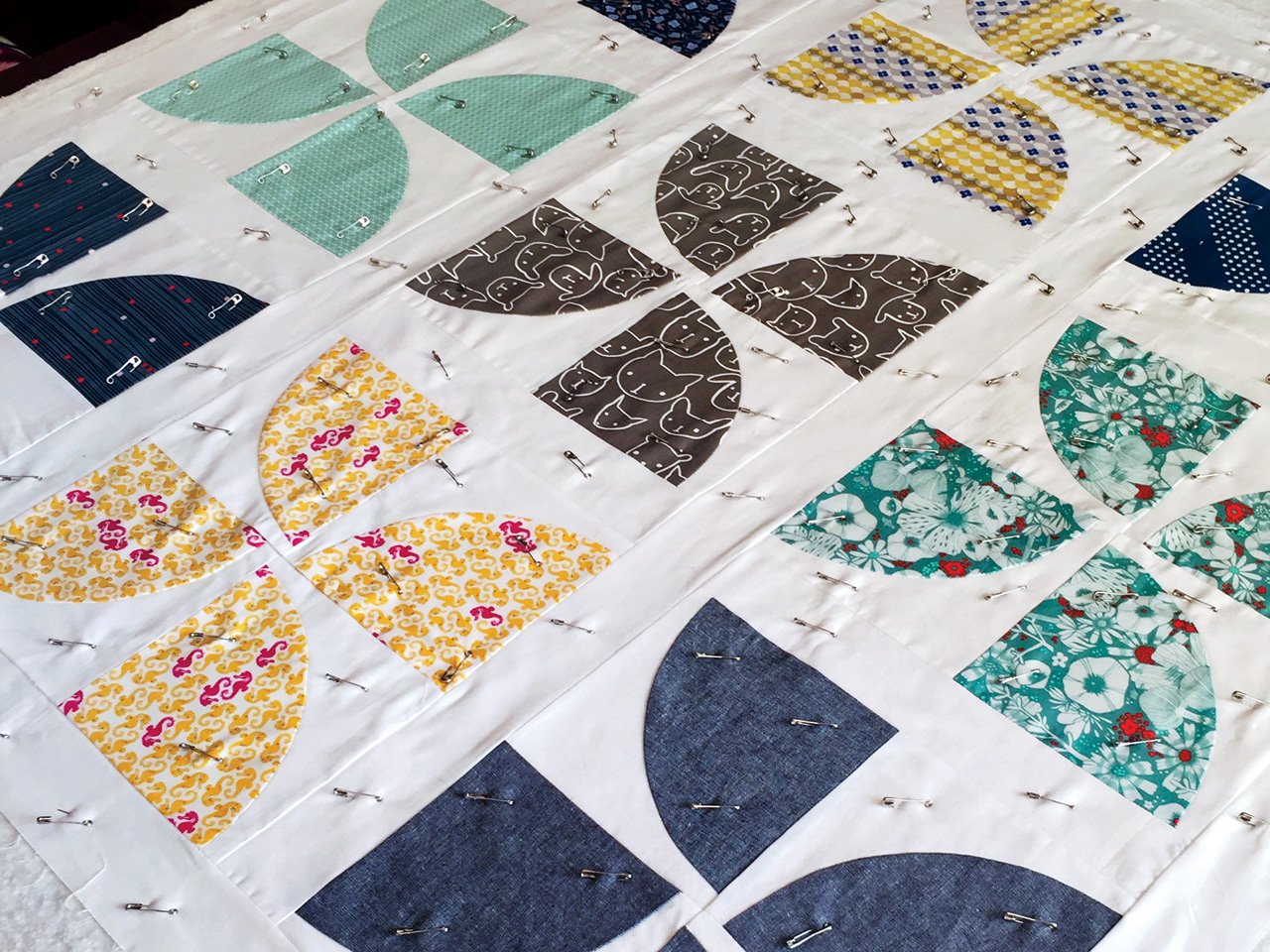 A pin-basted Pinwheel quilt for a friend’s new baby. Basting is the process of pinning (or stitching) the top, batting and backing together so you can quilt, or sew, through all three layers.