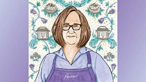 a woman with a bob haircut and purple apron stands near a background of cheesecakes and instant pots