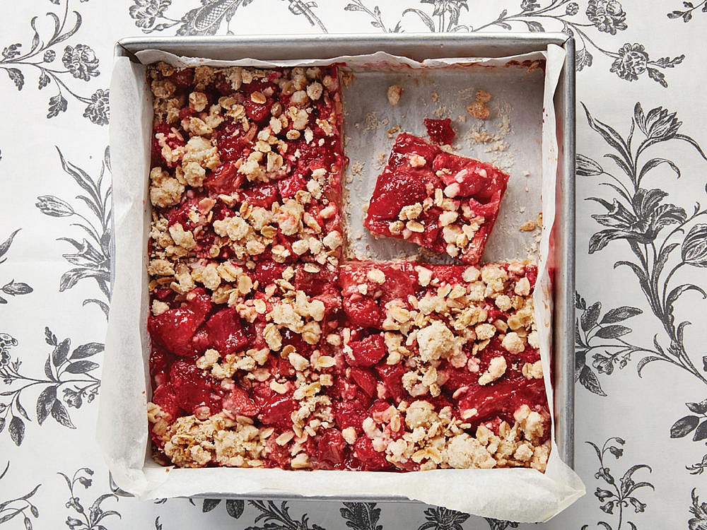 A tin of Vegan Strawberry-Rhubarb Oat Squares on a table with a floral design.