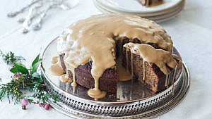 Curtis Stone's Sticky Toffee Pudding Cake on silver platter with toffee sauce drizzled overtop