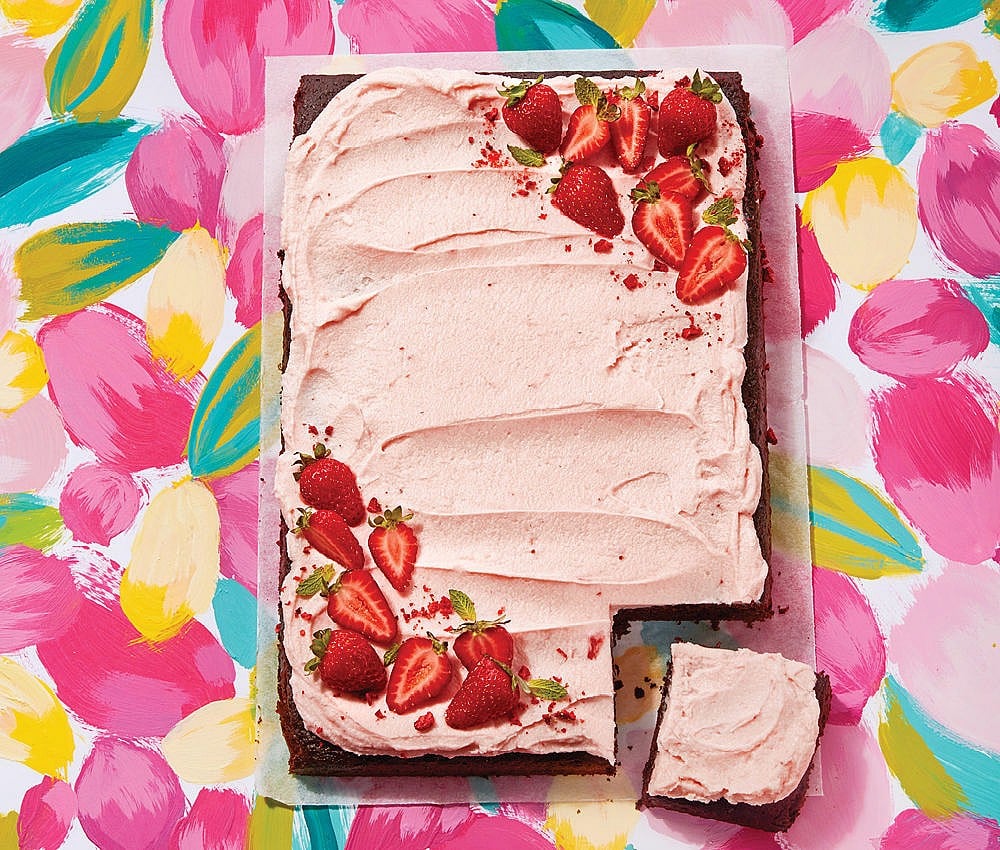 Chocolate cake with strawberry icing in front of a floral back drop