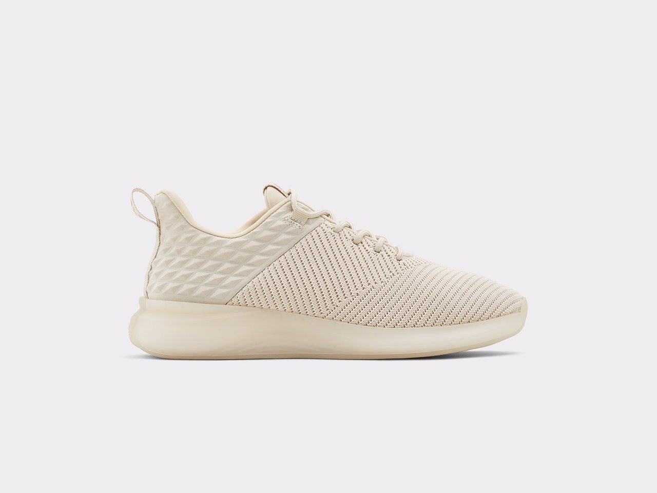 A pair of cream sneakers from Aldo made with sustainable algae-based foam against a light grey background.