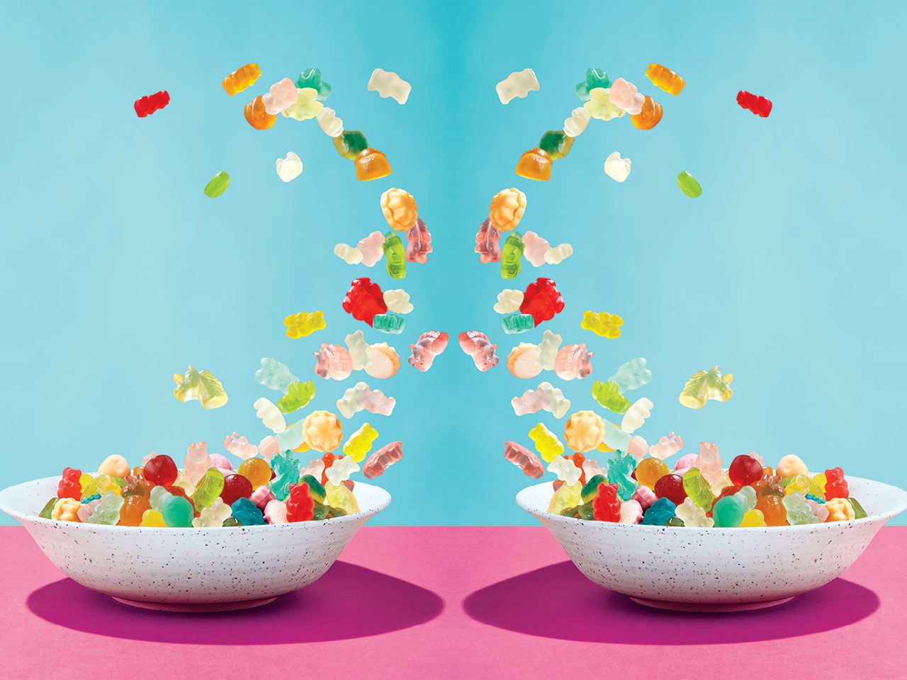 Colourful weed gummies flying out of two bowls