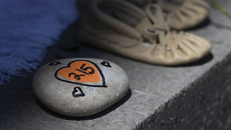 A photo of A rock with 215 painted on it is shown before a ceremony in Kingston, Ont., on May 31, 2021. The remains of 215 children were recently discovered on the grounds of the former Kamloops Indian Residential School. (Lars Hagberg/CP)