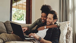 Shot of a happy young couple using a laptop while relaxing on a couch