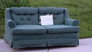 A teal couch with a sign marked "free" to illustrate an article on stooping and how to furnish your home for free.