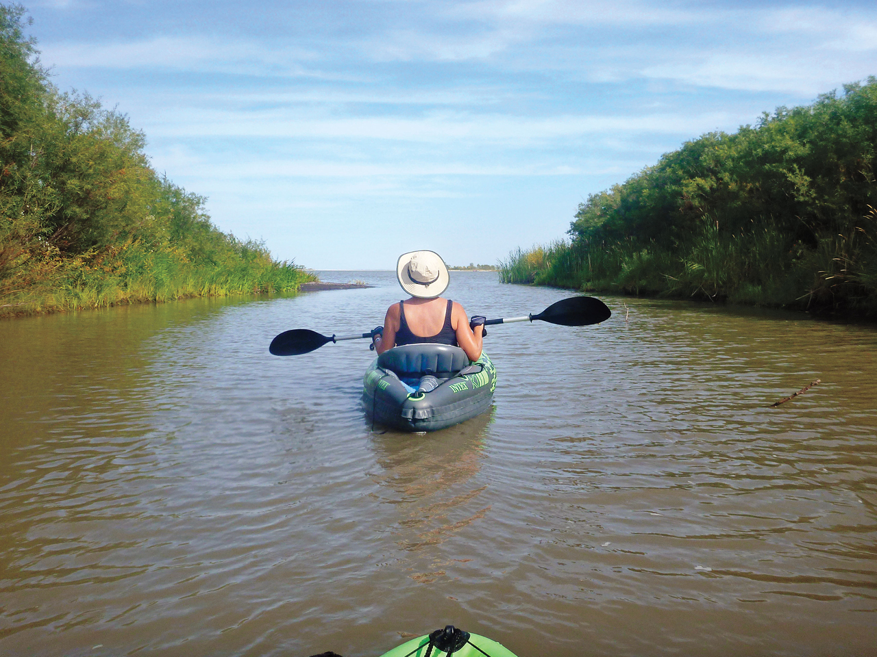 A photo of a woman paddling a river in an inflatable kayak